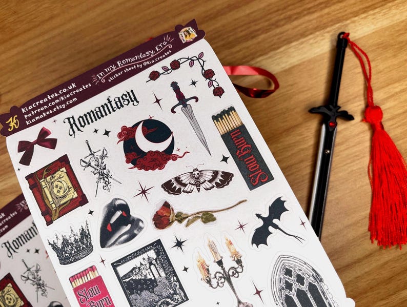 May include: A sheet of stickers with a romantic fantasy theme. The stickers feature a variety of images, including a book, a crown, a sword, a moon, a butterfly, a dragon, a candle, and a gothic window. The stickers are printed on white paper with black outlines and red accents.