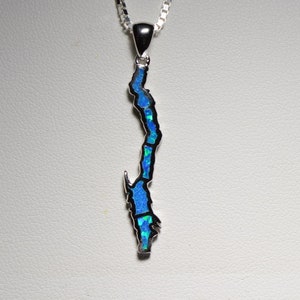 May include: A silver chain necklace with a pendant shaped like the outline of an island. The pendant is filled with blue and green opal stones.