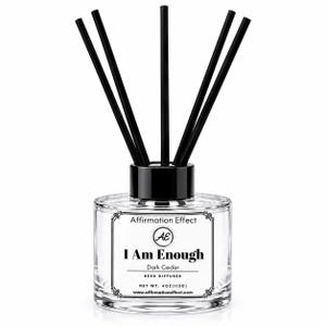 May include: A clear glass reed diffuser bottle with a black cap and five black reeds. The label features the text Affirmation Effect, AE logo, I Am Enough, Dark Cedar, Reed Diffuser, Net Wt. 4oz (113g), and www.affirmationeffect.com.