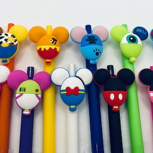 May include: A set of 12 colorful pens with cartoon character toppers. The toppers are shaped like Mickey Mouse ears and feature various characters, including a cow, a bee, a monster, and a dog. The pens are a fun and whimsical addition to any desk or pencil case.
