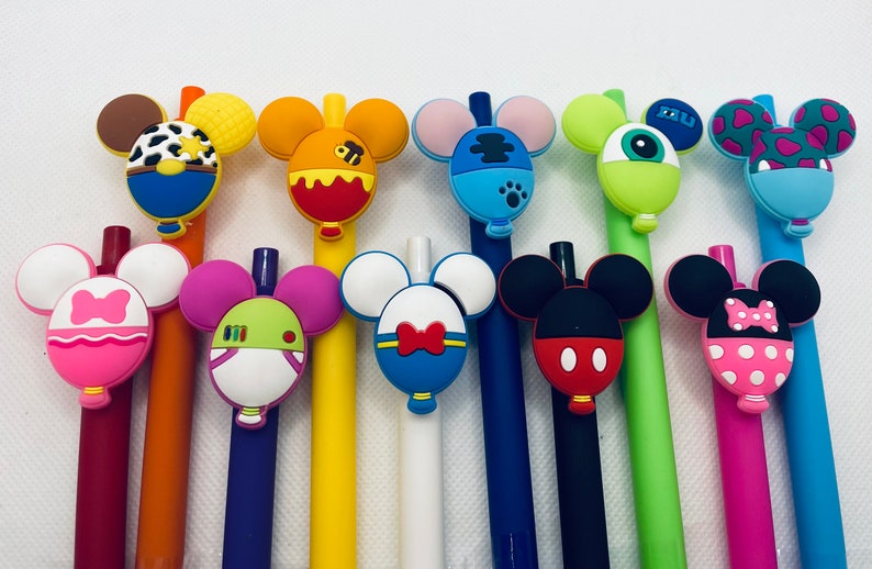 May include: A set of 12 colorful pens with cartoon character toppers. The toppers are shaped like Mickey Mouse ears and feature various characters, including a cow, a bee, a monster, and a dog. The pens are a fun and whimsical addition to any desk or pencil case.