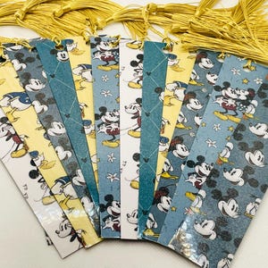 May include: A set of 10 colorful bookmarks featuring a vintage Mickey Mouse design. The bookmarks are made of paper and have a tassel on the top. The bookmarks feature different patterns and colors, including blue, yellow, and white.