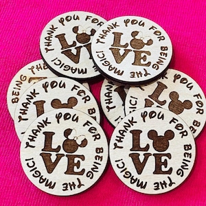 May include: A set of eight wooden round tags with a laser-engraved design. Each tag features a stylized Mickey Mouse head with the words "Thank You for Being the Magic! Love" in a circular design.
