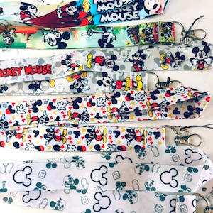 May include: A collection of colorful lanyards featuring Mickey Mouse designs. The lanyards display various patterns, including Mickey Mouse, Mickey Mouse's gloves, and the words "Mickey Mouse". Each lanyard has a metal clasp.