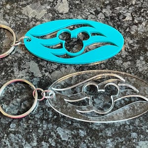 May include: Two keychains with a Mickey Mouse head silhouette and a wave design. One keychain is turquoise blue and the other is clear.