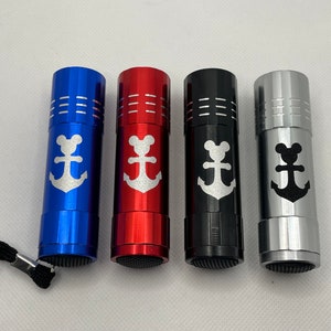 May include: Four small flashlights with a white anchor and a mouse head design. The flashlights are blue, red, black, and silver.