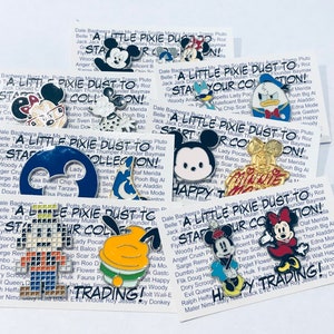 May include: A collection of colorful Disney character pins featuring Mickey Mouse, Minnie Mouse, Donald Duck, and other characters. The pins are arranged in a grid pattern on a white background. The text "A Little Pixie Dust To Start Your Collection!" is printed on each pin.