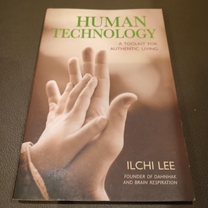 May include: Book cover with a photo of two hands touching. The title is "Human Technology: A Toolkit for Authentic Living" by Ilchi Lee, Founder of Dahnhak and Brain Respiration.