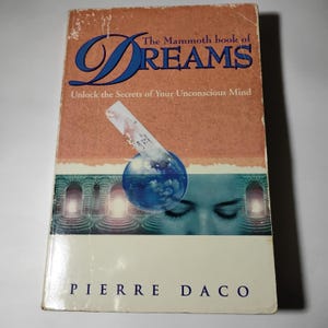 May include: A used paperback book titled "The Mammoth Book of Dreams" by Pierre Daco. The cover features a blue and orange design with the word "Dreams" in large, stylized blue letters. The cover also includes an illustration of a blue orb and a woman's face.
