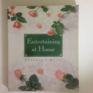 May include: A book titled "Entertaining at Home" by Annemarie Husted, with a green cover and pink roses on a white background.