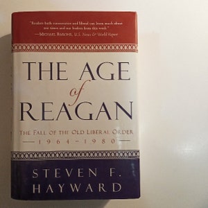 May include: A book titled "The Age of Reagan: The Fall of the Old Liberal Order 1964-1980" by Steven F. Hayward. The book cover is red, white, and blue with a quote from Michael Barone, U.S. News & World Report.