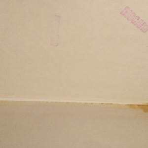 Puede incluir: Primer plano de una superficie blanca texturizada con un sello rosa que dice "DISCARD" en may&uacute;sculas.