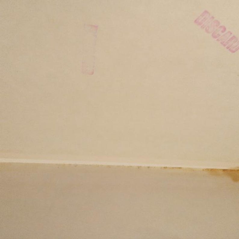 Puede incluir: Primer plano de una superficie blanca texturizada con un sello rosa que dice "DISCARD" en may&uacute;sculas.