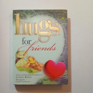 May include: A book titled "Hugs for Friends" with a gold foil title and a red heart illustration. The book features stories and personalized scriptures to encourage and inspire.