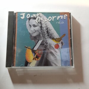 May include: A CD case with a colorful image of a woman with curly hair, a bird, and a guitar. The text on the case reads "Joan Osborne relish".