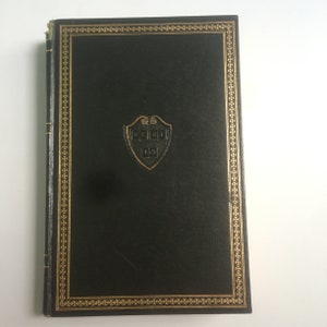 May include: A black leather-bound book with a gold border and a gold embossed shield with the text "YALE 1701" and "TAS" inside.