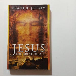 May include: A book cover with a gold background and the title "JESUS THE GREAT DEBATE" in large, bold letters. The author's name, "GRANT R. JEFFREY", is printed above the title in smaller letters. The cover features a faded image of Jesus' face.