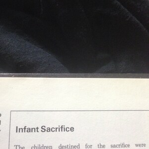 May include: A close-up of a page from a book with the heading "Infant Sacrifice". The text reads "The children destined for the sacrifice were"