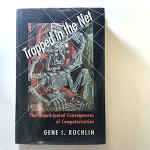 May include: A book cover with a black background and a robot illustration. The title of the book is "Trapped in the Net: The Unanticipated Consequences of Computerization" by Gene I. Rochlin.