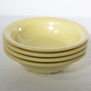 Puede incluir: Un conjunto de cuatro cuencos de cerámica de color amarillo pálido. Los cuencos son lisos y tienen una ligera curva en el borde.