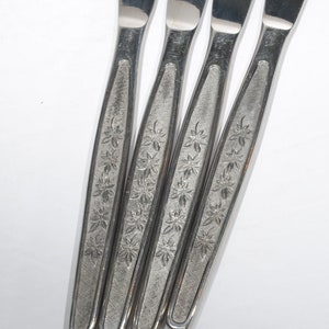 Puede incluir: Cuatro cuchillos de cena de plata con diseños florales en los mangos.