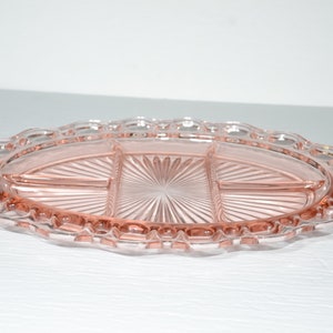 Pode incluir: Uma bandeja de servir de vidro rosa vintage com três compartimentos. A bandeja oval tem uma borda ondulada e um design de estrela no centro. Uma peça decorativa para servir lanches ou aperitivos.