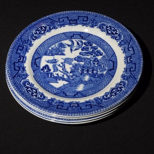 以下が含まれることがあります： 伝統的な中国の柳の模様が施された、青と白のセラミック製の皿が4枚重ねられています。皿は白い背景に青い縁取りが施され、中央には柳の木、橋、そして塔のデザインが描かれています。