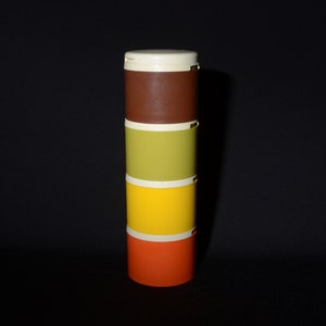 Puede incluir: Un contenedor apilable de cuatro niveles con un diseño marrón, verde, amarillo y naranja. El contenedor está hecho de plástico y tiene una tapa blanca.