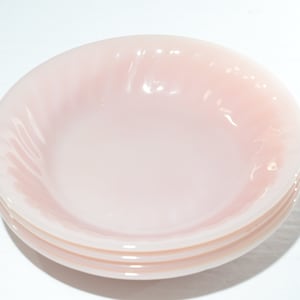 Pode incluir: Três tigelas de vidro rosa empilhadas umas sobre as outras. As tigelas têm um design ondulado e são feitas de um material translúcido.