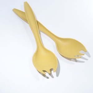 May include: A pair of yellow plastic salad servers with a spoon-like shape and a fork-like shape.
