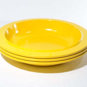 May include: Three yellow plastic bowls stacked on top of each other.