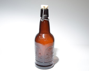 May include: A brown glass bottle with a wire swing top lid. The bottle has a decorative design of leaves and flowers.