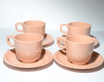 Puede incluir: Juego de cuatro tazas de té y platillos de cerámica de color melocotón. Las tazas y los platillos son todos del mismo tamaño y forma.
