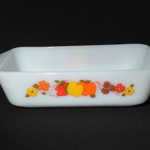 May include: White rectangular baking dish with a floral design featuring red, orange, yellow, and brown flowers and fruit. The dish has the word "Hilde" printed on the bottom.