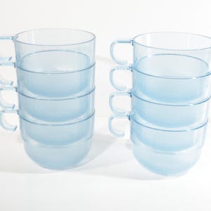 May include: Set of six light blue plastic cups with handles. The cups are stacked in two groups of three.