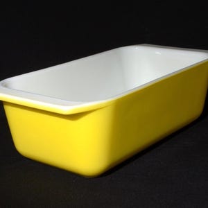 Op de afbeelding: Een rechthoekige ovenschaal met een heldergele buitenkant en een witte binnenkant. De schaal heeft een licht uitlopende rand en is ontworpen om in te bakken en te serveren. De algemene vorm is een klassieke cakevorm.