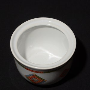 Puede incluir: Azucarero de cer&aacute;mica blanca con tapa. El bol tiene un patr&oacute;n geom&eacute;trico colorido en el exterior.