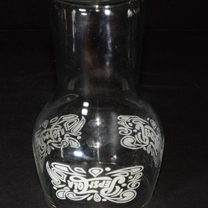 May include: A clear glass pitcher with a white etched design of the Pepsi-Cola logo and script. The design features stylized swirls and the words "Pepsi-Cola".