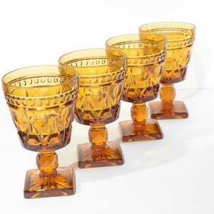 May include: Set of four amber glass goblets with a diamond pattern and square base.