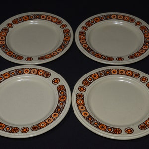 May include: Set of four beige ceramic plates with a brown and orange geometric pattern around the rim.