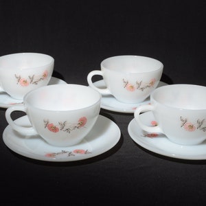 May include: Set of four white teacups and saucers with a floral design. The cups and saucers have a delicate pink and brown floral pattern.