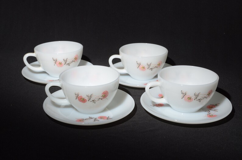 May include: Set of four white teacups and saucers with a floral design. The cups and saucers have a delicate pink and brown floral pattern.