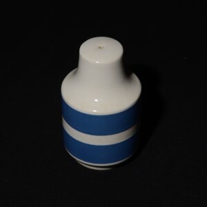 May include: A white ceramic salt shaker with two blue stripes around the middle.
