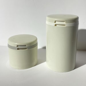 Könnte beinhalten: Zwei weiße Plastikbehälter mit grauen Deckeln. Der größere Behälter ist höher als der kleinere.