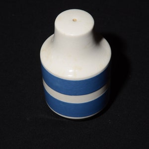 May include: A white ceramic salt shaker with two blue stripes around the middle.