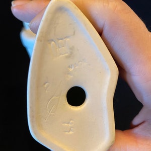 May include: White ceramic figurine with a hole in the bottom and the text "DEC" and "W.GER" on the bottom.