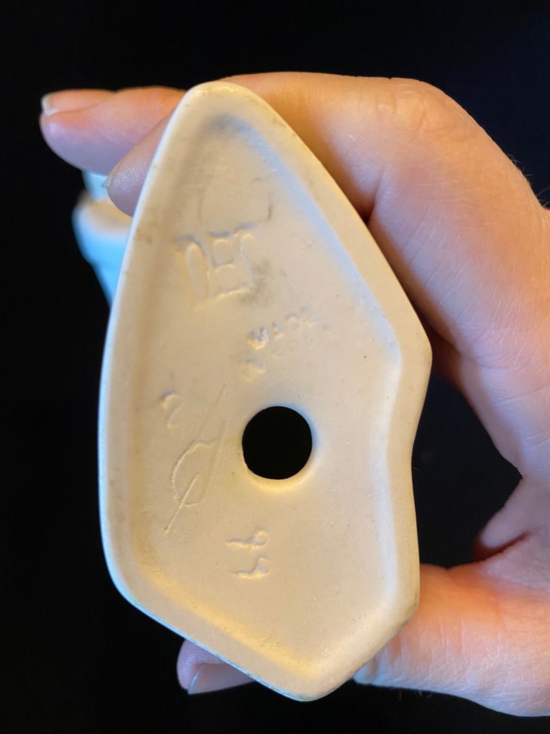May include: White ceramic figurine with a hole in the bottom and the text "DEC" and "W.GER" on the bottom.