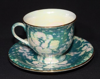 May include: A green and white teacup and saucer set with a floral pattern. The cup and saucer have a gold trim.