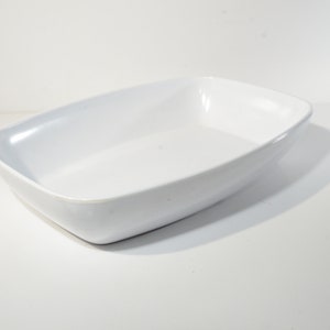 May include: A white rectangular ceramic baking dish with rounded edges.