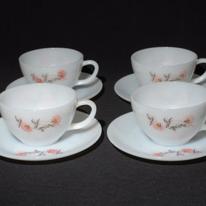 May include: Set of four white ceramic teacups and saucers with a floral design. The cups and saucers have a delicate pink and black floral pattern.